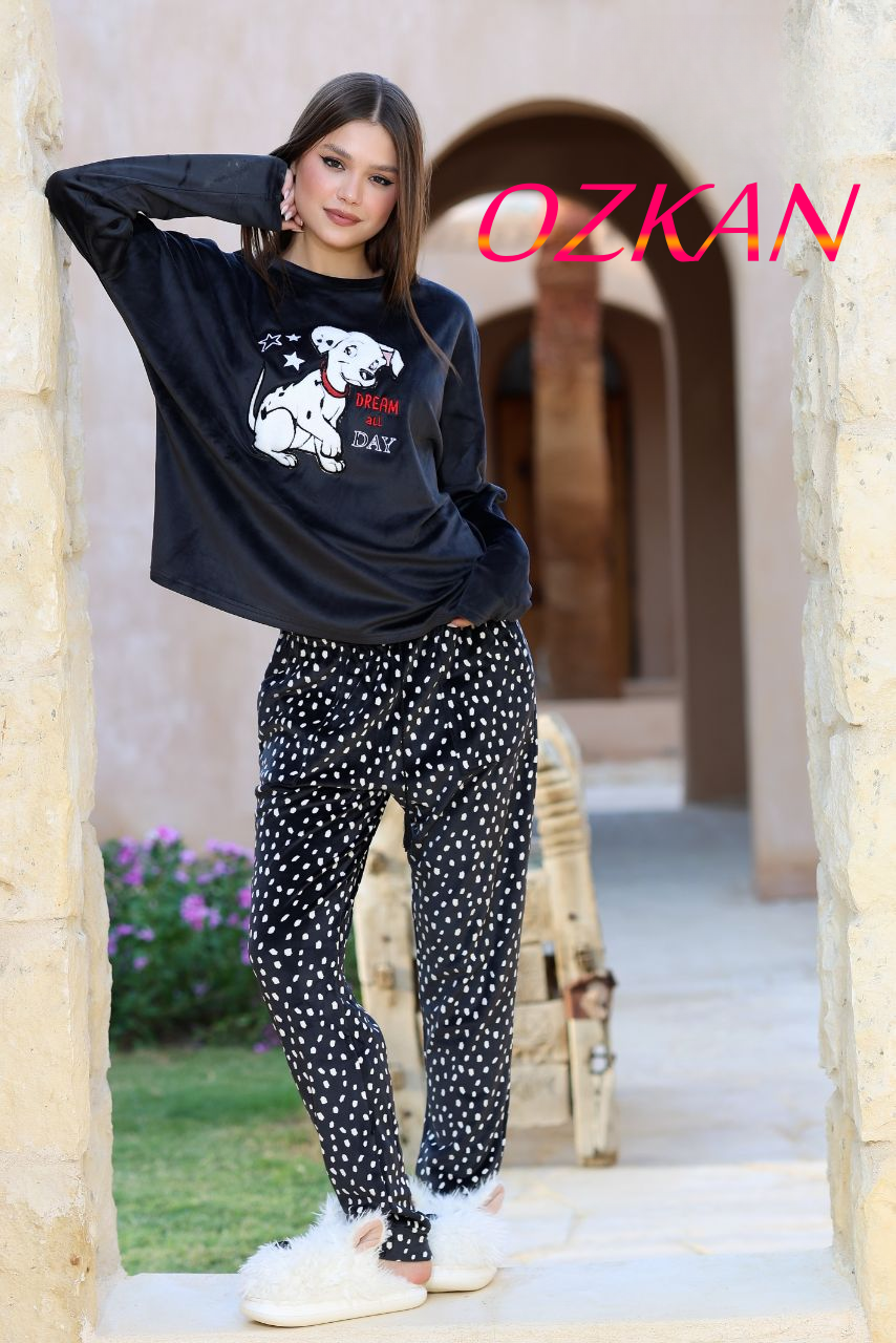 Woman wearing a black sweatshirt with a graphic design and polka dot pants in an outdoor setting, with 'OZKAN' branding.